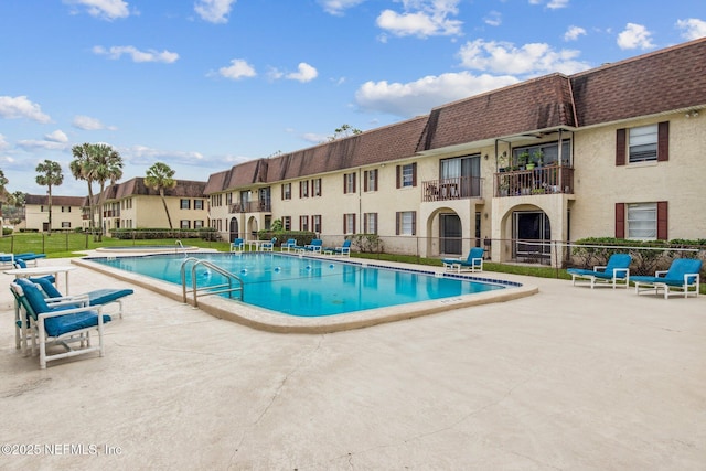 community pool with a patio and fence