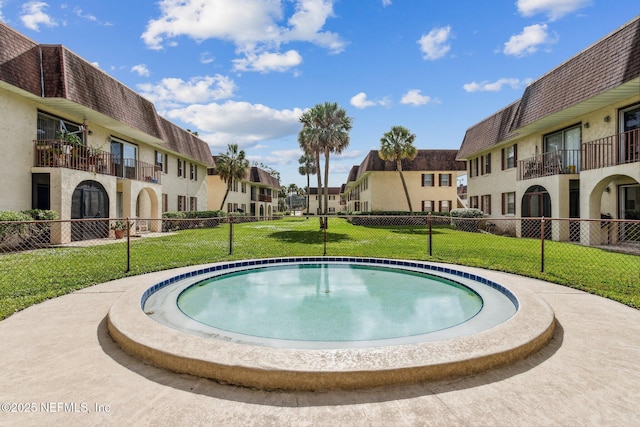 view of pool with a yard, fence, and a residential view