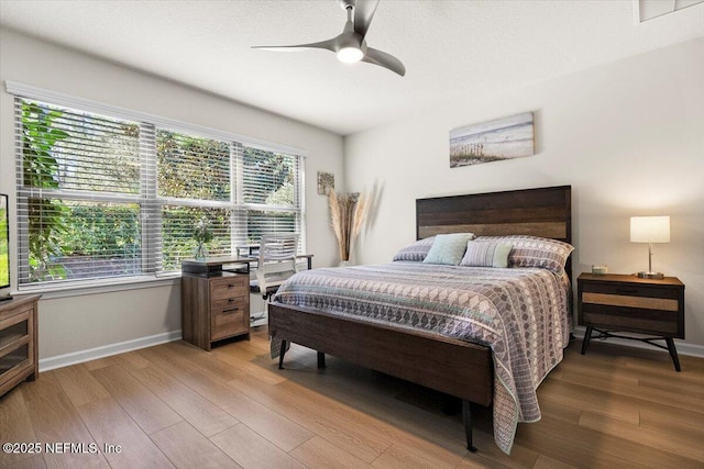 bedroom with multiple windows, light hardwood / wood-style flooring, and ceiling fan