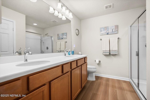 bathroom featuring hardwood / wood-style flooring, vanity, an enclosed shower, and a textured ceiling