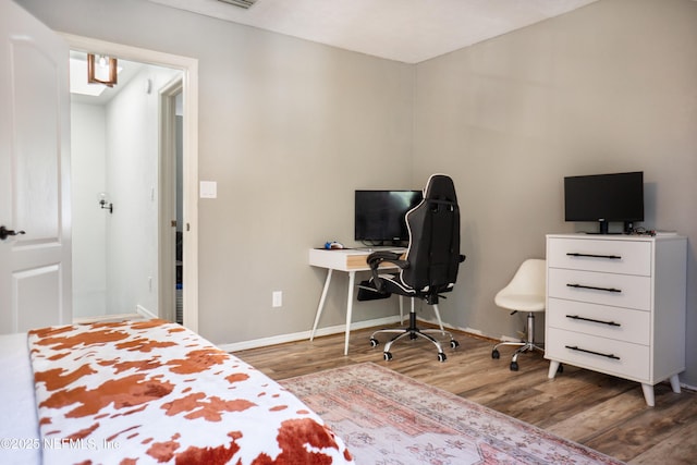 bedroom featuring visible vents, baseboards, and wood finished floors