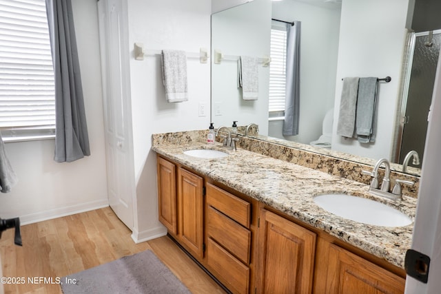 bathroom with double vanity, wood finished floors, a stall shower, and a sink