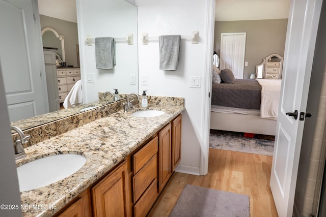 bathroom with double vanity, connected bathroom, a sink, and wood finished floors