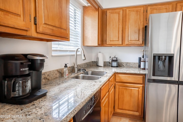 kitchen with light stone counters, a sink, stainless steel fridge with ice dispenser, brown cabinets, and dishwasher