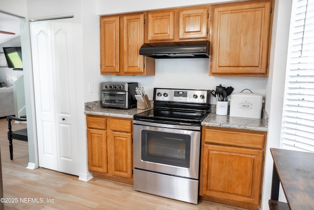 kitchen featuring light wood finished floors, a toaster, electric range, and under cabinet range hood