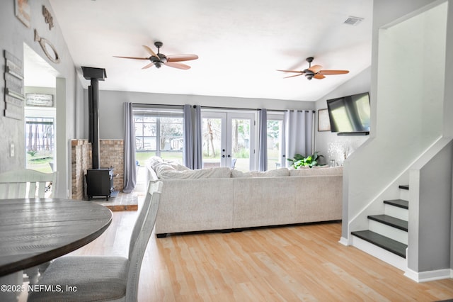 living room featuring hardwood / wood-style floors, vaulted ceiling, a wood stove, and ceiling fan