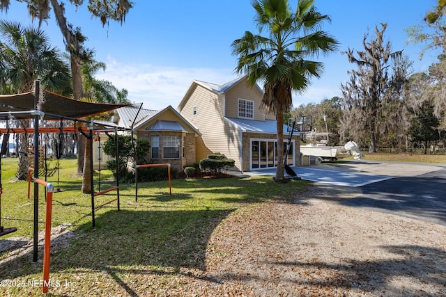 exterior space with metal roof, driveway, and a lawn