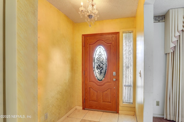 foyer entrance featuring a notable chandelier, light tile patterned floors, and a textured ceiling