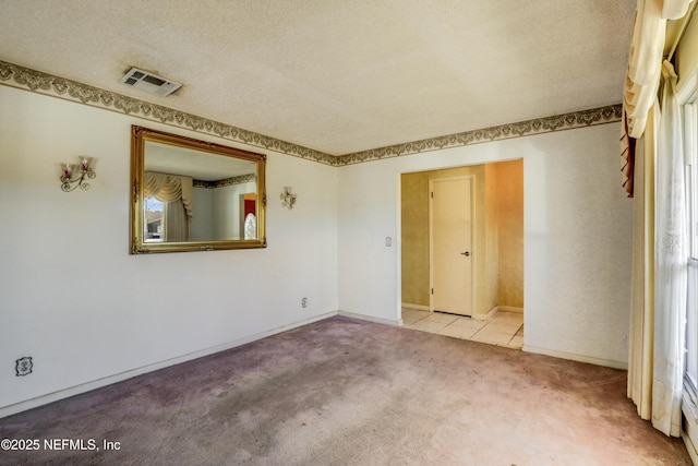 spare room with a textured ceiling and light carpet