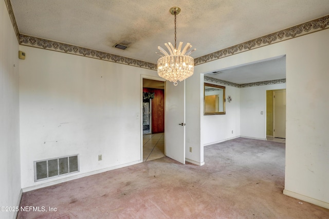 carpeted spare room with an inviting chandelier