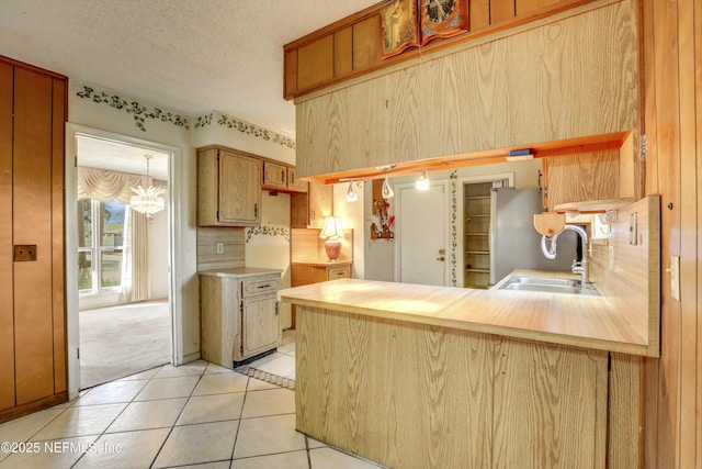 kitchen with an inviting chandelier, sink, decorative backsplash, a textured ceiling, and light tile patterned flooring