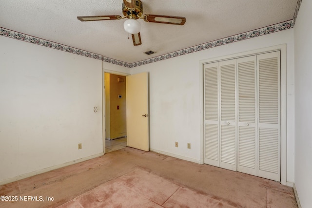 unfurnished bedroom featuring ceiling fan, light colored carpet, a textured ceiling, and a closet