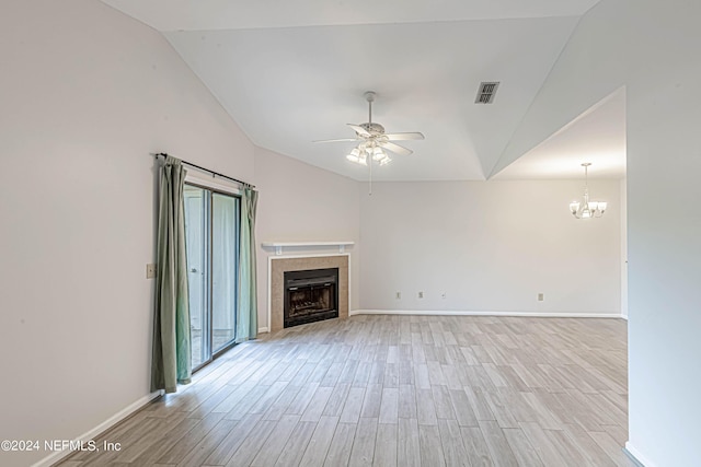 unfurnished living room with ceiling fan with notable chandelier, light hardwood / wood-style floors, lofted ceiling, and a tiled fireplace