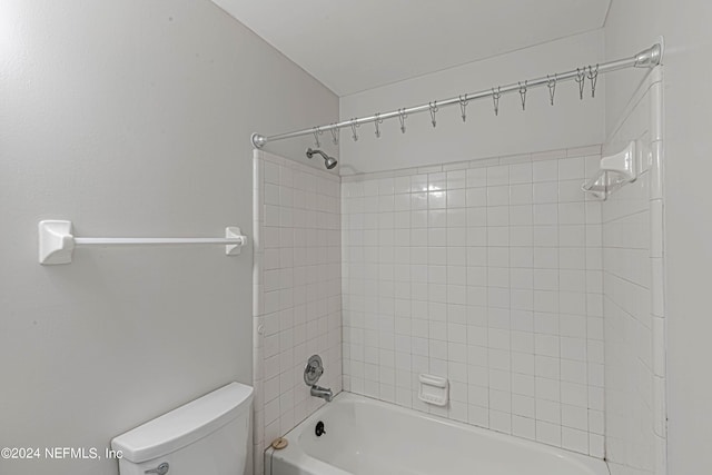 bathroom featuring tiled shower / bath combo and toilet