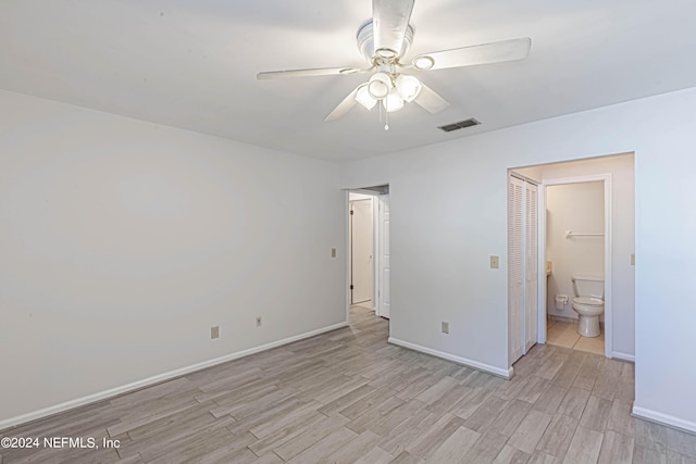 unfurnished bedroom with ceiling fan, ensuite bathroom, and light wood-type flooring