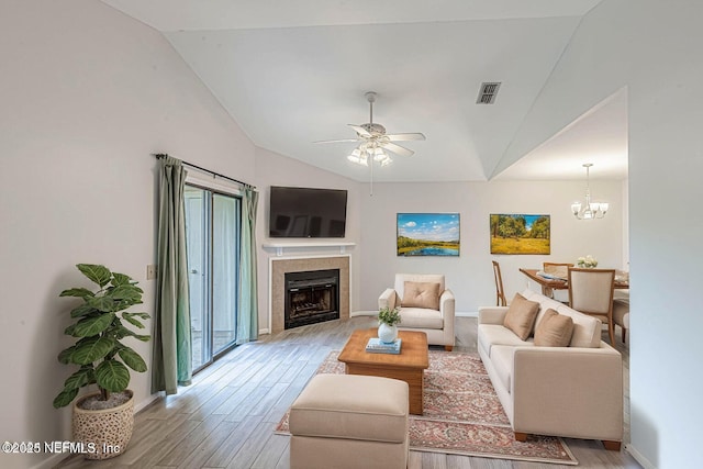 living room with ceiling fan with notable chandelier, light hardwood / wood-style floors, and vaulted ceiling