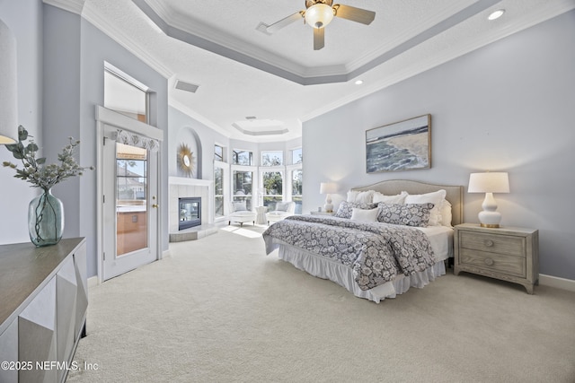 bedroom with a tray ceiling, crown molding, ceiling fan, and light colored carpet