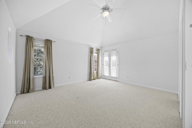 spare room with light carpet, plenty of natural light, and vaulted ceiling