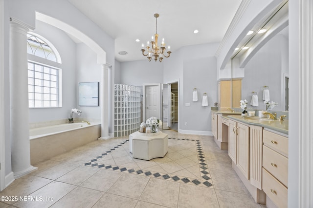 bathroom with tile patterned floors, vanity, ornate columns, and tiled bath