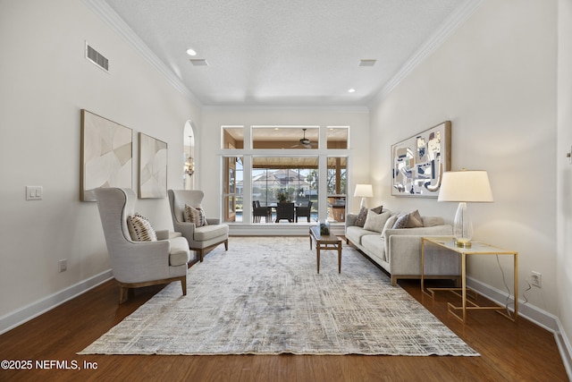 living room with ceiling fan, dark hardwood / wood-style floors, a textured ceiling, and ornamental molding