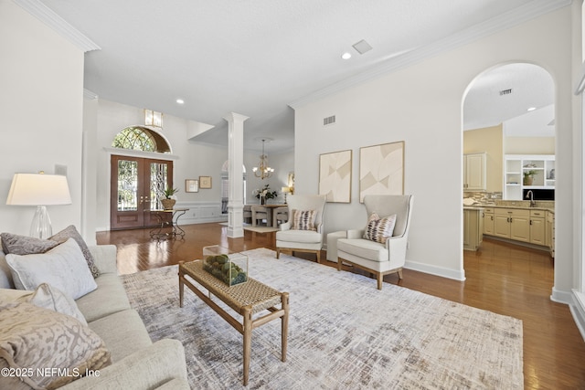 living room featuring sink, french doors, light hardwood / wood-style flooring, and a chandelier