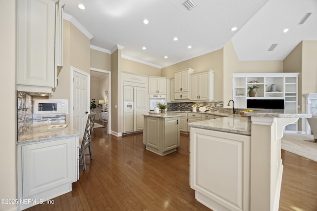 kitchen featuring white oven, light stone counters, kitchen peninsula, decorative backsplash, and a breakfast bar