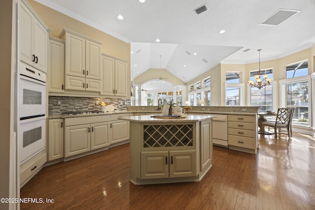 kitchen featuring pendant lighting, a center island, ceiling fan with notable chandelier, tasteful backsplash, and kitchen peninsula