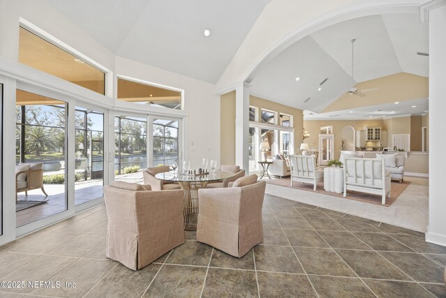 dining area featuring tile patterned floors, a water view, high vaulted ceiling, and ceiling fan