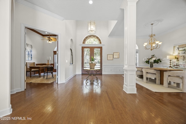 entryway with ornate columns, french doors, crown molding, a textured ceiling, and hardwood / wood-style flooring