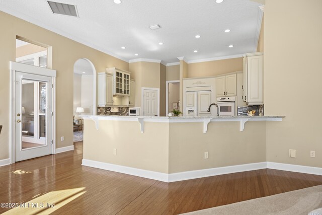 kitchen featuring white appliances, crown molding, a breakfast bar area, and backsplash