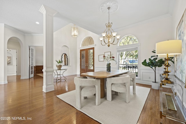 dining space with dark wood-type flooring, crown molding, french doors, and a chandelier