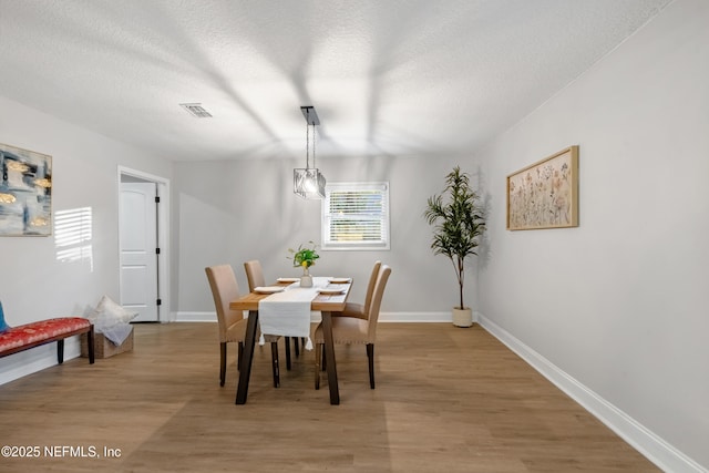 dining room featuring a textured ceiling and light wood-type flooring