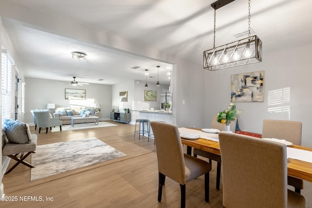 dining area with ceiling fan, wood-type flooring, and a textured ceiling