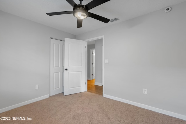 unfurnished bedroom with a closet, light colored carpet, and ceiling fan