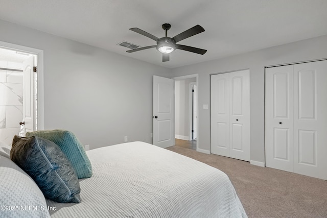 carpeted bedroom with ceiling fan and two closets