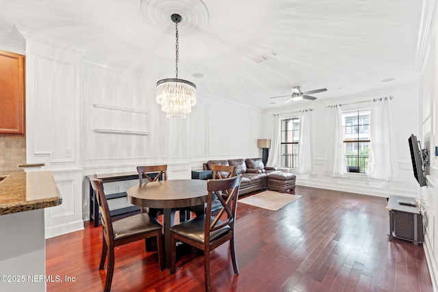 dining space featuring crown molding, dark hardwood / wood-style flooring, and ceiling fan with notable chandelier