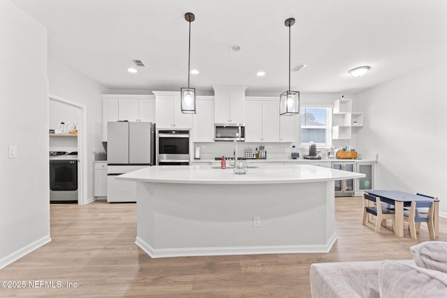 kitchen with washer / clothes dryer, white cabinetry, hanging light fixtures, and stainless steel appliances