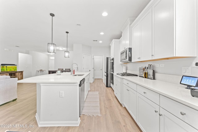 kitchen with white cabinetry, pendant lighting, a kitchen island with sink, and appliances with stainless steel finishes