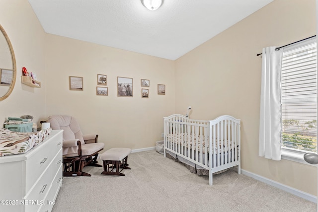 bedroom with multiple windows, light colored carpet, and a nursery area