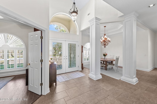 foyer entrance with french doors, decorative columns, and a wealth of natural light