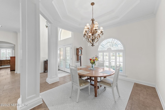 tiled dining room featuring french doors, ornate columns, ornamental molding, a tray ceiling, and an inviting chandelier