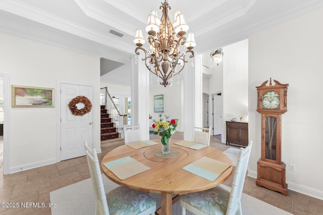 dining area with a raised ceiling, ornamental molding, and a notable chandelier