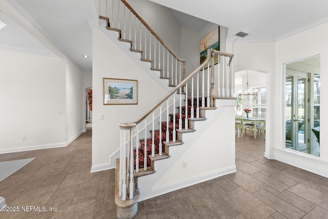 stairs featuring a chandelier and ornamental molding