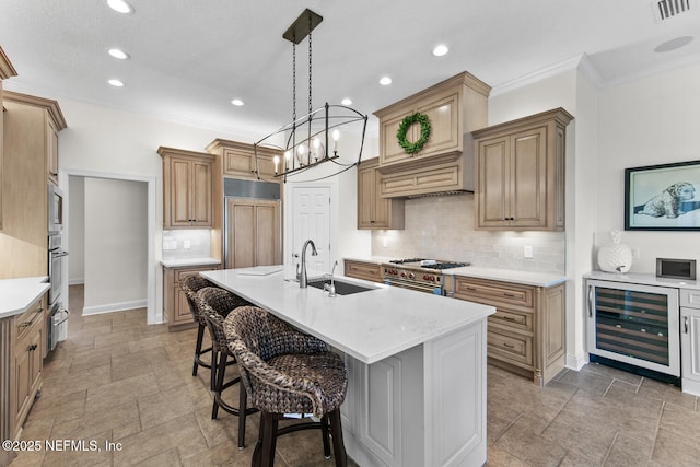 kitchen with tasteful backsplash, premium appliances, beverage cooler, sink, and an island with sink