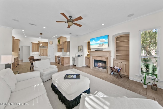 living room with built in shelves, plenty of natural light, crown molding, and ceiling fan