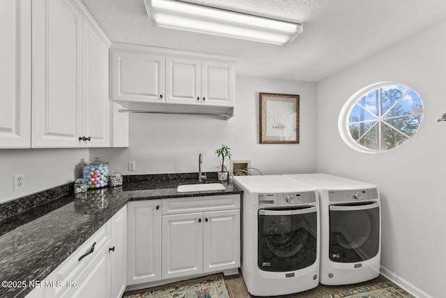 laundry area featuring washer and clothes dryer, sink, cabinets, and a textured ceiling