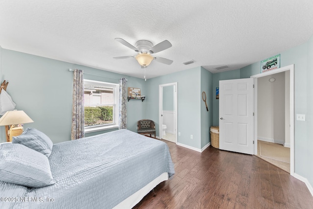 bedroom featuring a textured ceiling, dark hardwood / wood-style flooring, ensuite bath, and ceiling fan