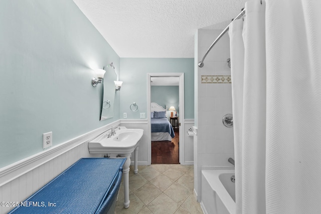 bathroom with a textured ceiling, tile patterned floors, shower / bathtub combination with curtain, and sink