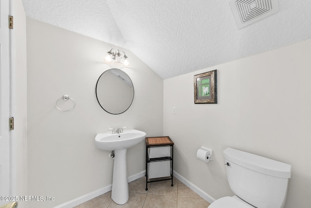 bathroom featuring tile patterned flooring, a textured ceiling, toilet, and lofted ceiling