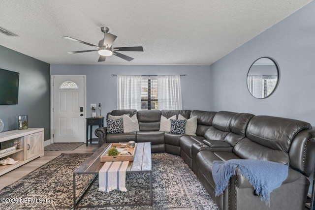 living room featuring hardwood / wood-style flooring, ceiling fan, and a textured ceiling